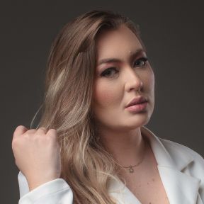 Foto da Dra Nattany de perfil com a mão em pose seria